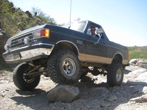 1991 Ford Bronco - This lifted 1991 Ford Bronco navigates a rocky trail with its front tire on a large boulder.