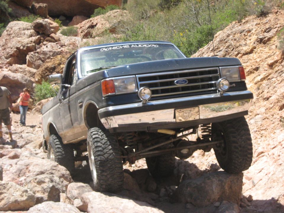 Dark blue Ford F-Series truck with off-road tires navigating rocky terrain