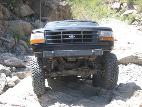 1991 Ford Bronco - This Ford Bronco is shown from the front, navigating a rocky, off-road environment.