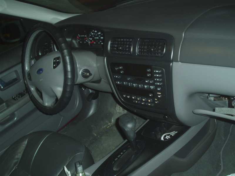 Ford sedan interior dashboard showing steering wheel, center stack controls, and console shifter