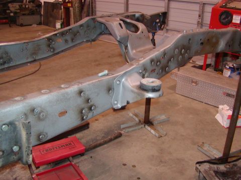 1991 Ford Bronco - The bare frame of a vehicle is shown, supported by stands in a workshop setting.