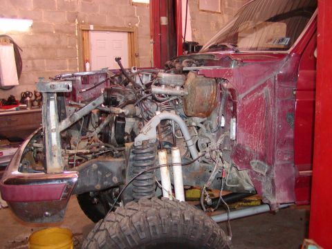 1991 Ford Bronco - The front end of a 1991 Ford Bronco is shown disassembled in a workshop, revealing its engine and suspension components.