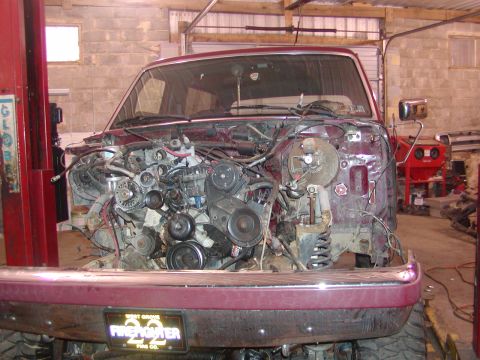1991 Ford Bronco - Front view of a maroon Ford truck/SUV in a shop with the hood, grille, radiator and core support removed, exposing the V8 engine, serpentin…