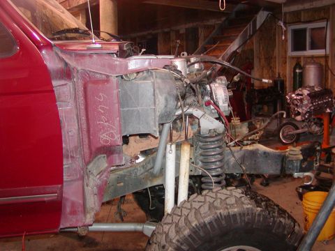 1991 Ford Bronco - Driver's-side view of a burgundy truck with its front clip stripped off, exposing the engine bay with alternator, coil spring and shock, gr…