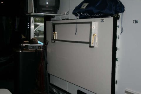 1993 Ford C-350 (Centurion Conversions) - The interior of a trailer shows a fold-down bed and a television mounted above.