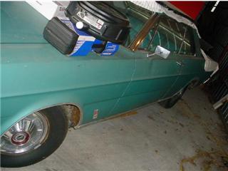 1972 Ford Ranchero - Side view of a teal sedan with some items placed on its hood.