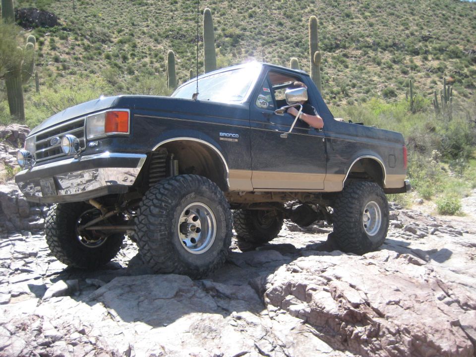 Lifted black and tan 1991 Ford Bronco on rocky terrain