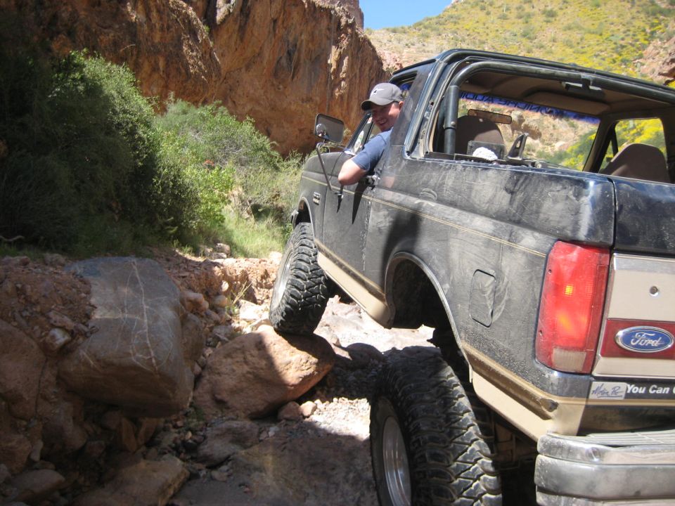 1991 Ford Bronco navigating a rocky off-road path with a driver visible