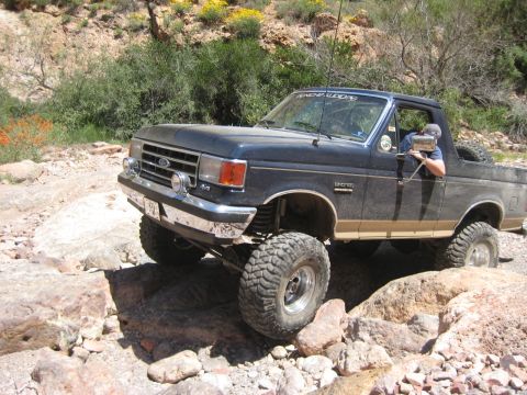 1991 Ford Bronco - A Ford Bronco tackles a challenging rocky trail in a desert environment.