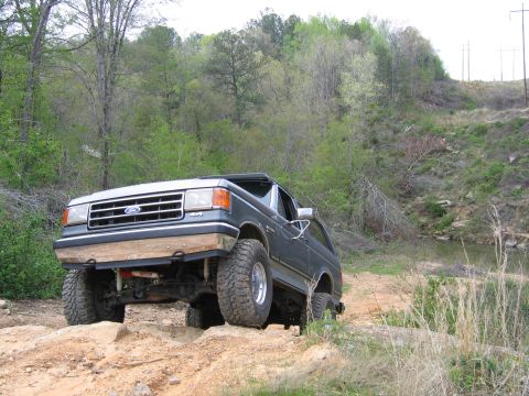 1989 Ford Bronco - Ford Bronco navigating rough terrain on a wooded trail.