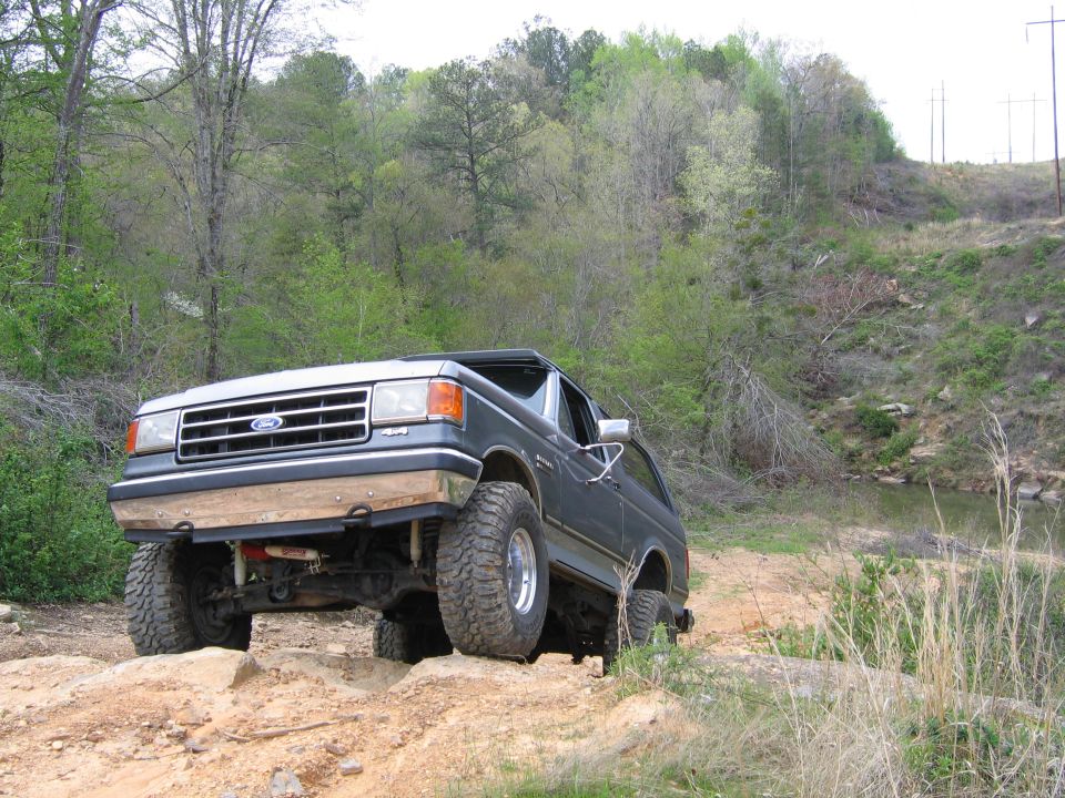 1989 Ford Bronco on a dirt trail with large tires, front wheels elevated
