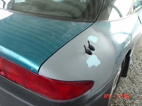 1993 Ford Probe - The rear of a car shows primer patches and two holes where antennas were likely removed.
