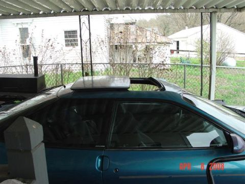 1993 Ford Probe - Side view of a teal coupe with its sunroof open, parked under a carport.