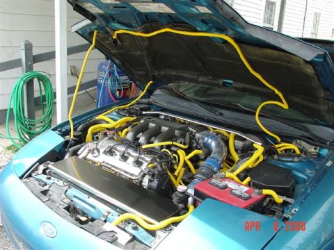 1993 Ford Probe - Engine bay of a 1993 Ford Probe, yellow hoses and an aftermarket intake system.