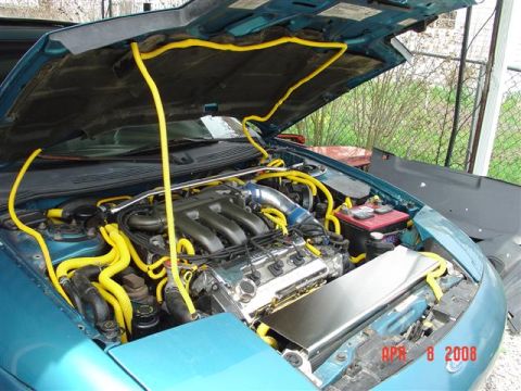 1993 Ford Probe - The engine bay of a teal car is visible with yellow hoses and a red battery.
