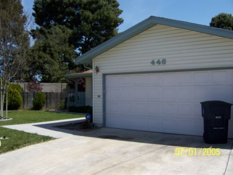 1991 Ford Bronco - This photo shows a residential house with a white garage door and a trash bin next to it.