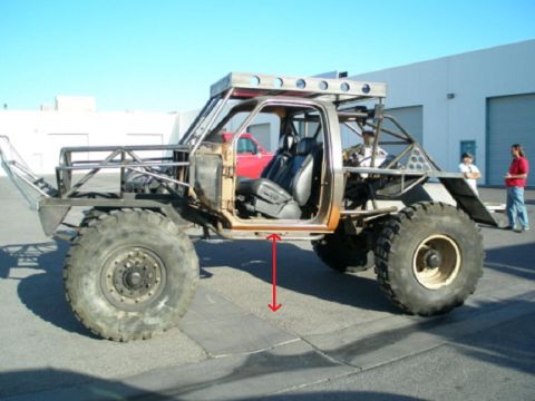 1991 Ford Bronco - A heavily modified off-road vehicle with a custom roll cage and oversized tires is shown from the side, with a red truck visible in the bac…
