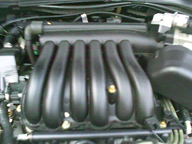 Close-up of black V6 intake manifold with curved runners in an engine bay
