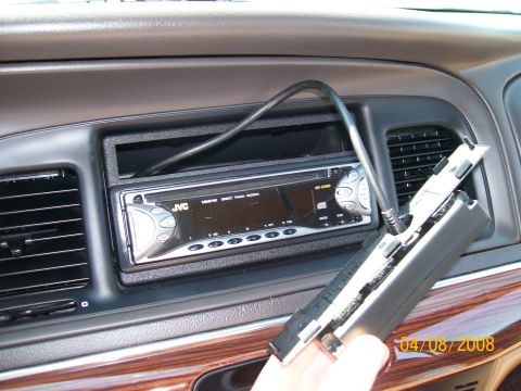 1995 Mercury Grand Marquis - Close-up of an aftermarket JVC KD-S580 CD head unit installed in the double-DIN dash opening of a gray-interior car, with an empty pocket a…