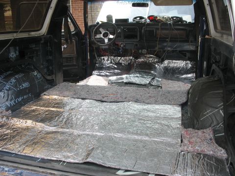 1978 Ford Bronco - The interior of an SUV is being worked on, with sound-deadening material installed on the floor and door panels.