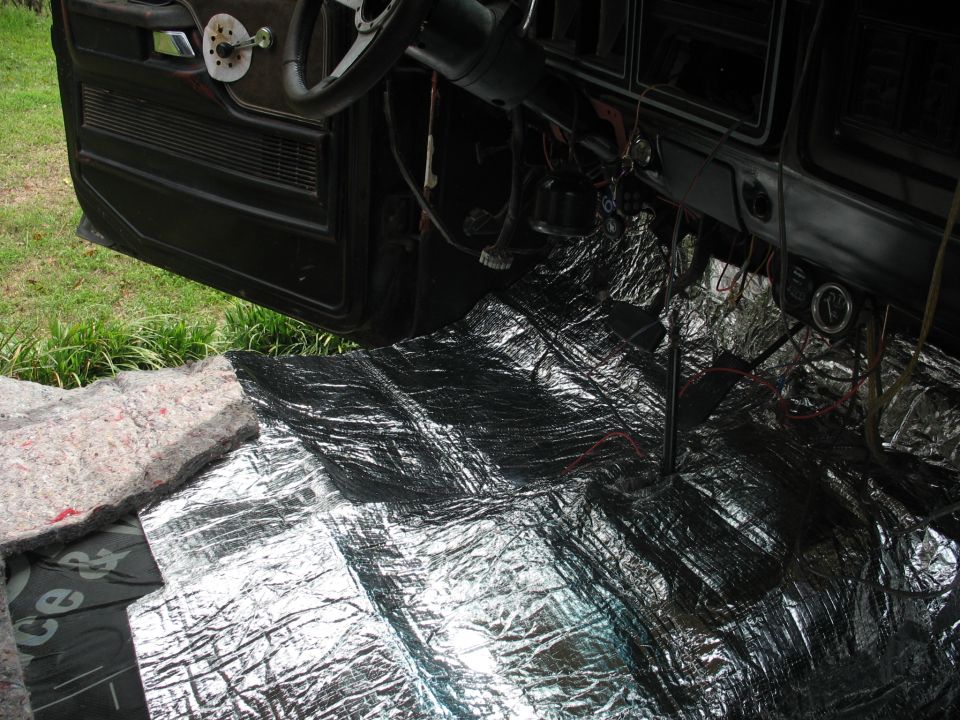 Car interior showing soundproofing material on the floor and door panel removed