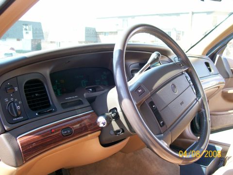 1995 Mercury Grand Marquis - Driver's side interior of a Mercury sedan with tan leather, simulated woodgrain dash trim, and an illuminated green digital instrument clus…