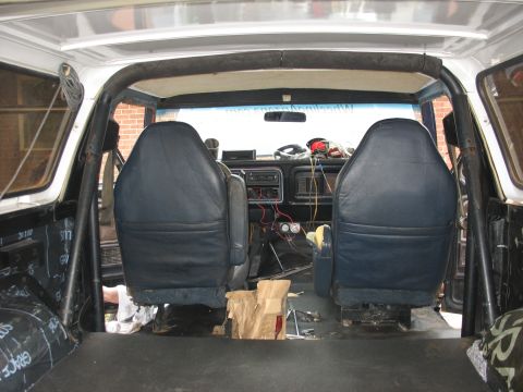 1978 Ford Bronco - The interior of a 1978 Ford Bronco shows dark blue seats, a roll cage, and a cluttered dashboard with exposed wiring.