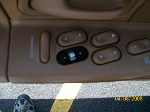 1995 Mercury Grand Marquis - Close-up of a tan driver's door armrest panel with the power window switch bank, mirror control joystick with amber indicators, and "WINDOW…