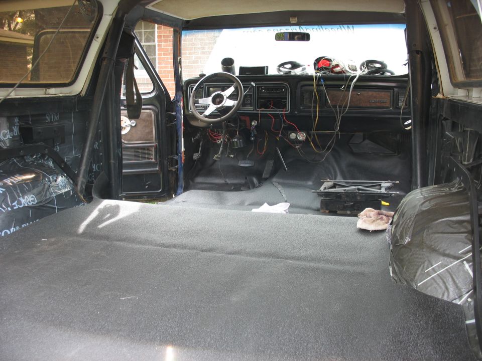 1978 Ford Bronco interior, dark grey carpet, exposed wiring, aftermarket steering wheel, removed passenger seat