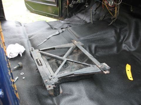 1978 Ford Bronco - Jack mechanism and wiring visible inside a vehicle with a new black floor liner installed.