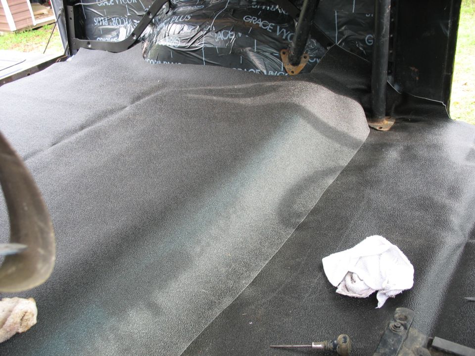 Interior floor of a vehicle with new carpet and sound deadening material installed on the rear floor and behind the seats
