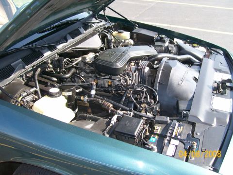 1995 Mercury Grand Marquis - The engine compartment of a car is shown with the hood open, revealing the engine and surrounding components.