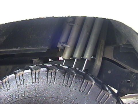 1984 Ford Bronco - Close-up view of the rear suspension system, including shocks and a tire, on a vehicle.