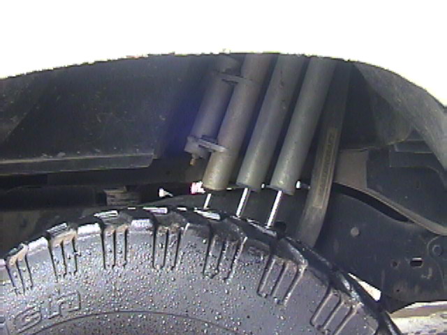 Triple shock absorber setup in a rear wheel well above a knobby tire