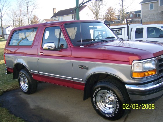 Red and silver Ford Bronco with chrome wheels, parked on a driveway