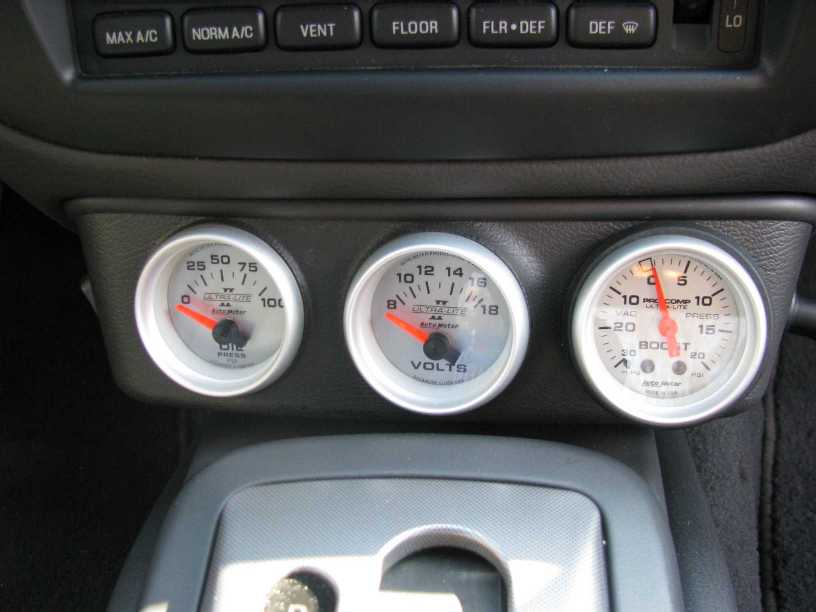 Triple Auto Meter Ultra-Lite gauges (oil, volts, boost) mounted below a car's climate controls