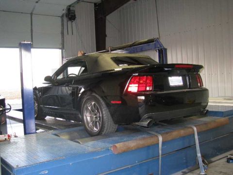 2003 Mercury Marauder - A black convertible is positioned on a dynamometer for testing. The vehicle's rear is visible, showing its taillights and spoiler.