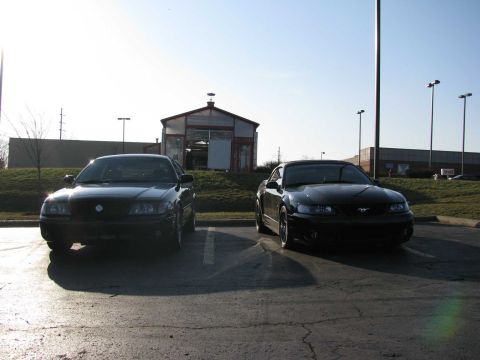 2003 Mercury Marauder - Two black cars are parked in a lot with a building in the background.