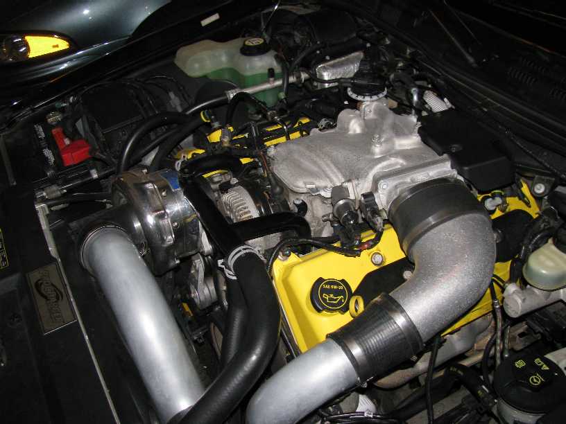 Supercharged V8 engine bay with yellow valve covers and polished ProCharger head unit