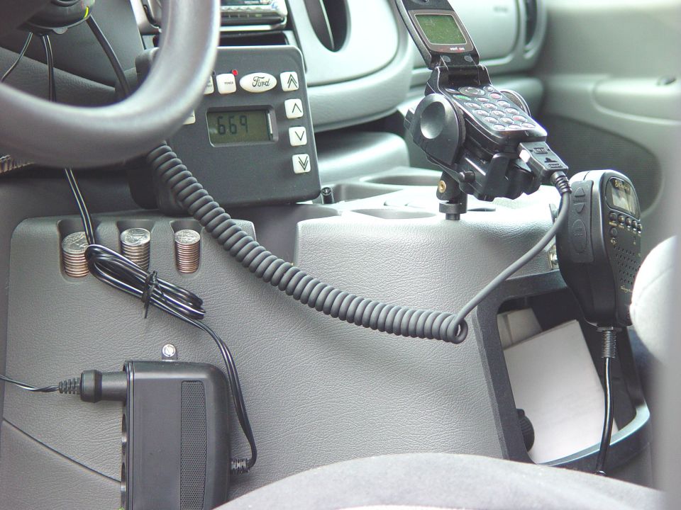 Ford van interior center console with Ford control display, mounted flip phone, radio mic, and coin holder