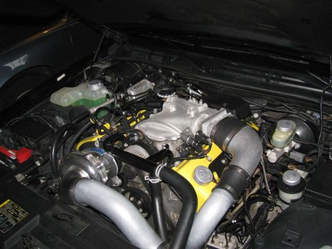 2003 Mercury Marauder - Close-up of a modified V8 engine, a prominent supercharger and bright yellow valve covers.