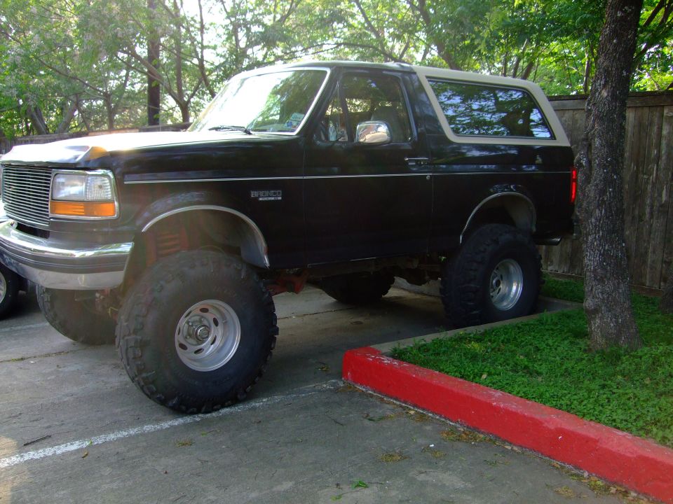 1992 Ford Bronco parked on pavement with grass and trees