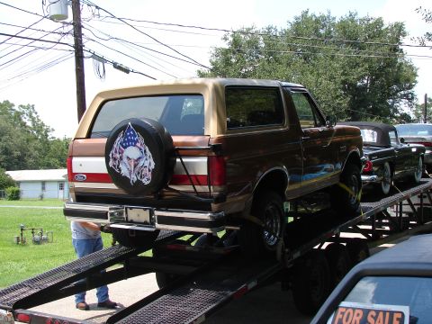 1989 Ford Bronco - A brown Ford Bronco is loaded onto a car carrier, with other vehicles visible behind it.