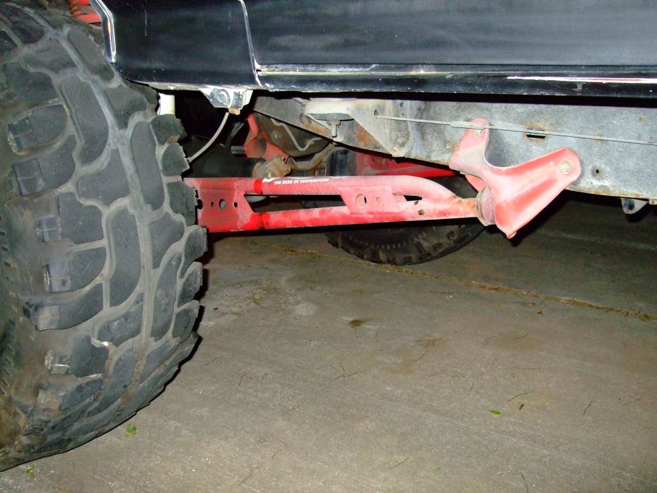 Black truck body, red suspension components, and a large off-road tire
