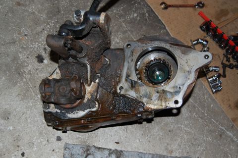 1994 Ford Bronco - A greasy transfer case, likely from a 4x4 vehicle, rests on a concrete surface with tools nearby.