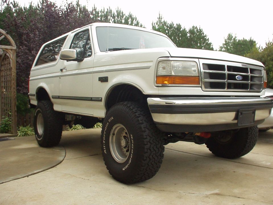 White lifted Ford Bronco SUV on BFGoodrich tires, front 3/4 view on driveway