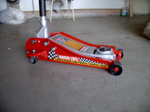 1986 Ford Bronco - A red low profile service jack with a 6000 lbs capacity is shown in a garage setting.