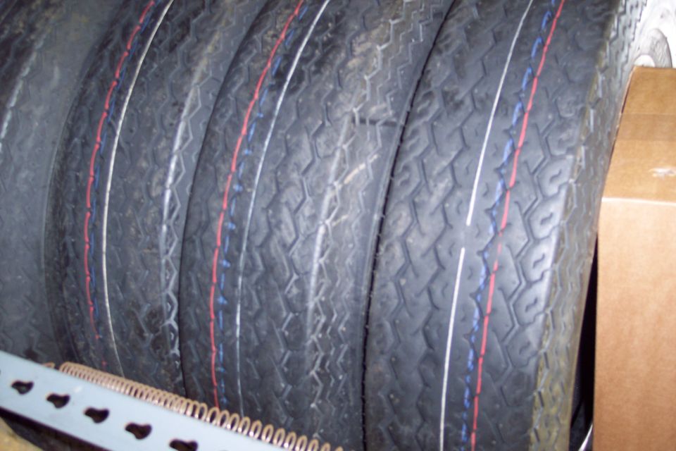 Stack of four tires with red and blue stripes on the sidewalls