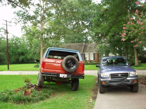 1983 Ford Bronco - A red and blue 1983 Ford Bronco is parked in a driveway next to a blue Toyota Tacoma.