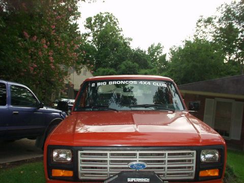 1983 Ford Bronco - A red Ford truck with a "2 BIG BRONCOS 4X4 CLUB" sticker is parked next to a blue truck.